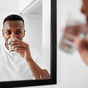 a man rinsing with water while looking in a mirror