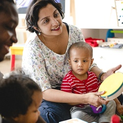 parent playing an instrument with their child in a classroom