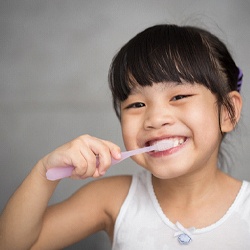 child smiling and brushing their teeth