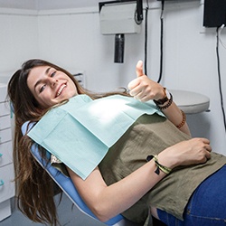 Woman smiling with thumb up laying in dental chair