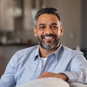 Mature man in blue shirt smiling on couch