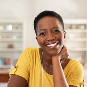 Woman in yellow shirt smiling in living room at home