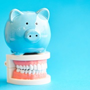 Piggy bank standing on top of a model of teeth