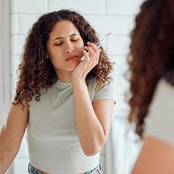 Woman experiencing discomfort while brushing her teeth