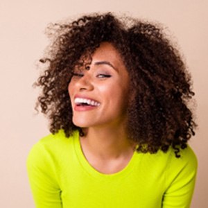 Woman in neon shirt smiling with veneers