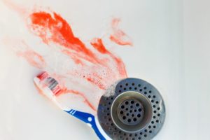 blood and toothpaste going down sink drain