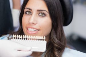 A dentist comparing porcelain veneers to a patient’s smile.