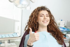young woman in dental chair giving thumbs up before receiving oral conscious sedation