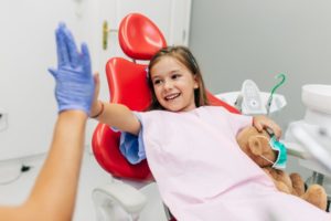 Smiling young girl high-fiving her Buckhead children’s dentist