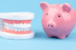 Set of teeth next to pink piggy bank 