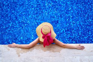 Woman with hat sitting in swimming pool